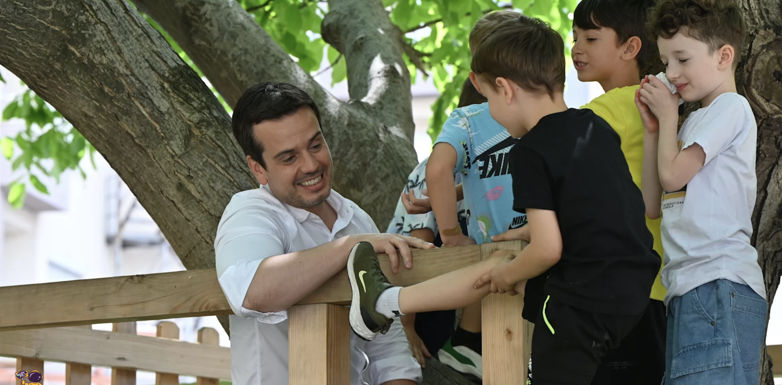 Ivan Novakovski laughing with young students climbing a tree on campus